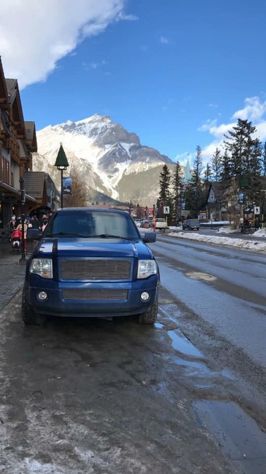 Blue Ford Expedition SUV Limousine parked in Banff with Rocky Mountains in background