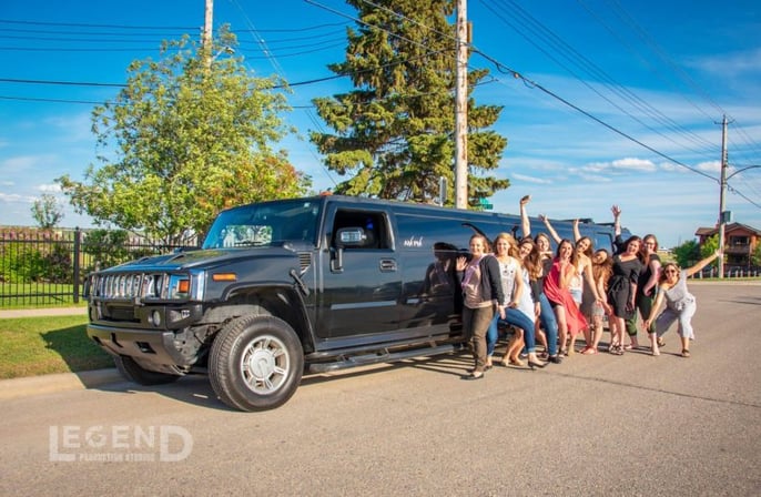 Group celebration in front of black Hummer Limousine