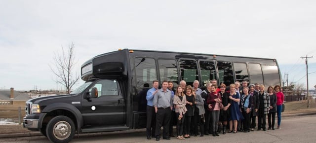 Group celebrating in front of black party bus