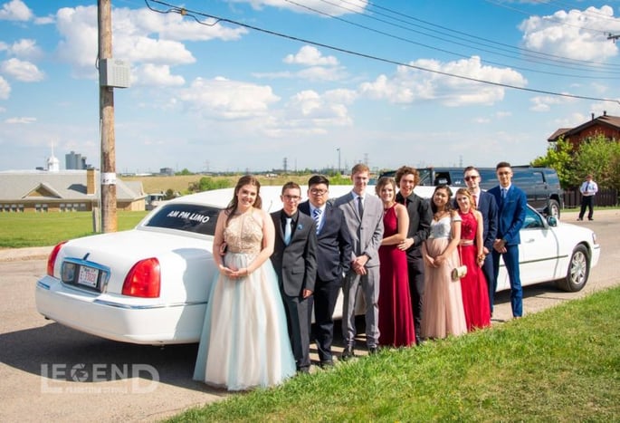 High School Grads pose front of a White Lincoln Stretch Limousine