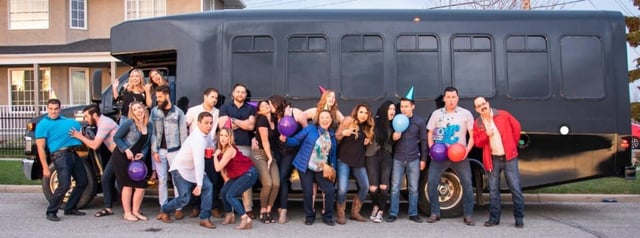 Group celebration with balloons outside of black party bus
