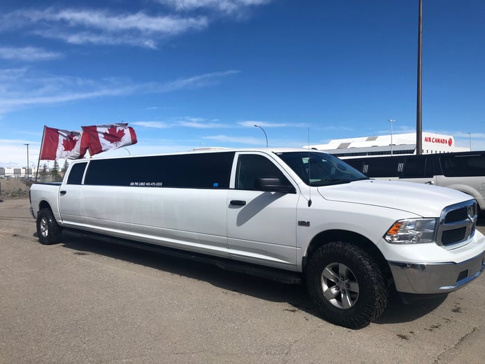White Dodge Ram Limousine with Canada flags standing in truck bed